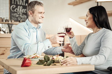 Charming man and happy woman holding glasses of wine