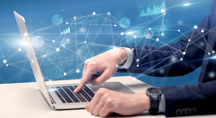 Businessman typing on laptop with linked reports charts grapghs around
