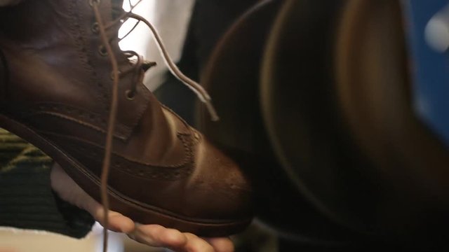 Hands holding a leather boot on a workshop polishing belt as it spins repeatedly - version 2
