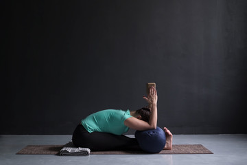 woman practicing yoga, Seated forward bend pose, using block and bolster