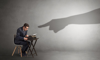 Shadow hand pointing at a small afraid worker
