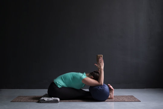 woman practicing yoga, Seated forward bend pose, using block and bolster