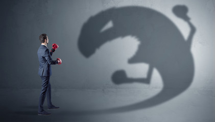 Fototapeta premium Businessman with boxing glove fighting with a big monster shadow 