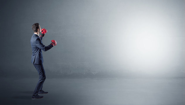 Businessman fighting with boxing gloves in an empty space
