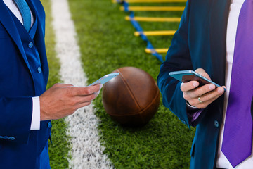 Friends using his mobile phone and watches football on smartphone in the park.