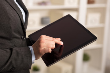 Business woman below chest using tablet in a homey environment
