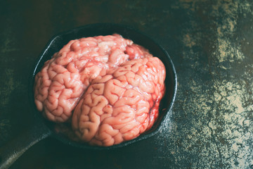 Pink brain before cooking on black metal frying pan. Raw meat. Offal
