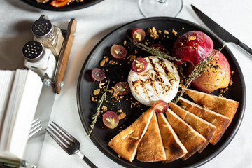 Grilled camembert with baked apple and grapes with slices of bread cakes
