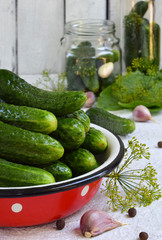 Fresh cucumber in metal bowl. Making of conservation from organic vegetables on a light background. Homemade organic green pickles in a jar. Copy space.