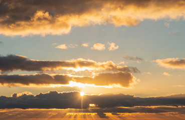 Beautiful colorful vibrant golden hour sunset skyscape with cloud formation and setting sun