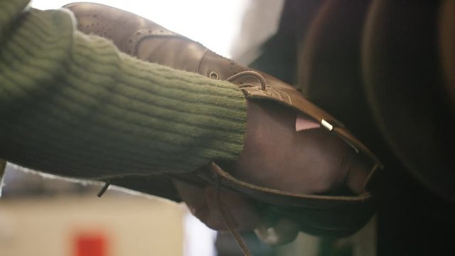 Hands holding a leather boot on a workshop polishing belt as it spins repeatedly