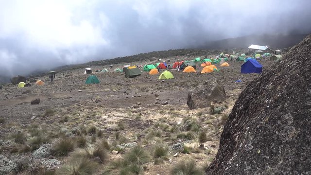 Wide Shot of a Mount Kilimanjaro Hikers Camp with Tents and Huts. Foggy Clouds moving Fast above the Camp