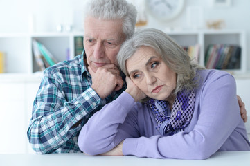 Portrait of sad senior couple posing at home