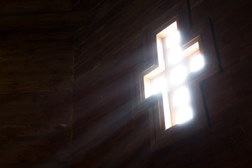 Light goes into a wooden church through the cross-shaped window