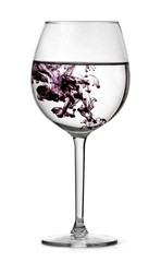 Glass with water and drop of violet ink. Half full glass for wine isolated on white background with clipping path.