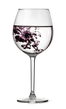 Glass with water and drop of violet ink. Half full glass for wine isolated on white background with clipping path.