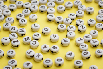 LOVE word made of white round plastic blocks on a yellow background with many other blocks with letters around