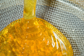 Pouring fresh honey through filter sieve while harvesting