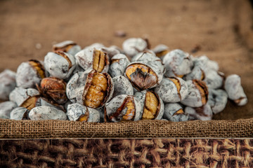 Ripe chestnuts on old wooden table and sack napkin close up with copy space. Roasted Chestnuts for Christmas 