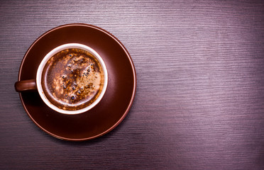 a cup of coffee and chocolate candies on a dark background.