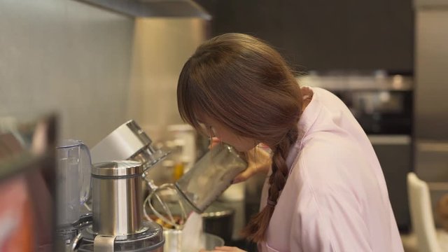 Mother adds flour and dough loosener into mixer. Girl takes extra products from fridge and brings them to her mum. Mum tells to wait a bit as overall dough is not ready yet for additional ingredients.