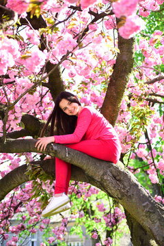 Her casual style. Pretty girl with fashion look. Fashionable young lady on flowering tree. Little girl in fashion wear in spring garden. Fashion clothing for spring