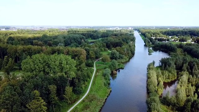 Drone flying over the canal in the forest with a village in the background. Dronten, Netherlands.
