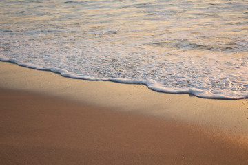 Fototapeta na wymiar Beach floor during sunset with white foam and orange sand