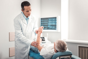 Grey-haired retired man having his hand examining after car accident