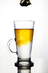 Brewing of hot beverage with tea bag in glass cup on white background