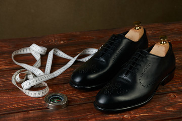 Business travel concept with pair of black mens shoes, compass and measuring tape