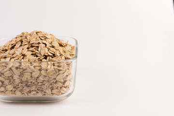 Dry rolled oatmeal in bowl isolated on white background. Top view