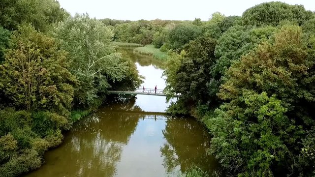 Drone view of people walking across a bridge in the park. Dronten Netherlands.
