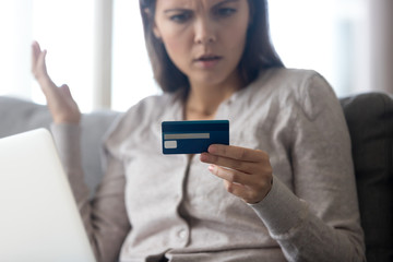 Confused female customer angry with rejected online payment having problem paying in internet or debt, frustrated woman holding credit card mad about failed transaction scam fraud concept, close up