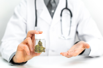 Doktor im weißen Kittel hält Cannabis Hanf als Medizin in einer Medikamenten Dose