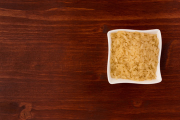 white rice in bowl on wooden table background