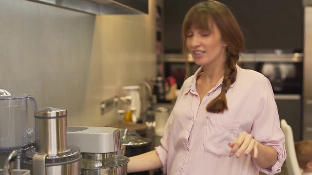 A mother cooks lunch for her family. She is happy because her kids help her and they all spend time together. She uses mixer and lets the daughter together with her add some flour into the bowl.