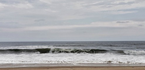 Rolling wave under a cloudy sky.