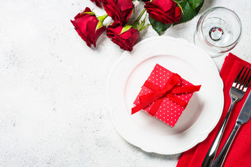 Romantic holiday table setting with plate, roses and present.