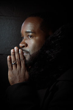 Profile close up of a black man with praying hands