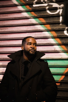 African American Man Wearing All Black In A Colorful Urban Environment 