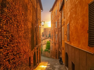 Sonnenuntergang in den Gassen von der historischen Stadt Siena in der Toskana in Italien - obrazy, fototapety, plakaty
