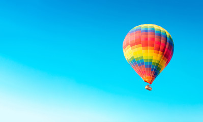 Fototapeta premium Colorful hot air balloon isolated on blue sky background. Colorful hot air balloon flying over at fairy chimneys in Nevsehir, Goreme, Cappadocia Turkey. 