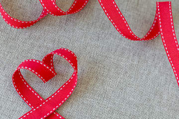 Heart made from red ribbon on linen textile with space for text, Valentine's Day concept.