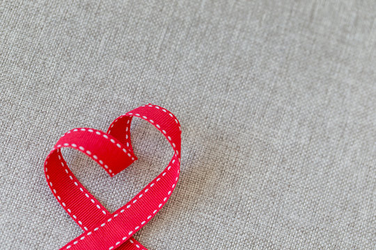 Heart made from red ribbon on linen textile with space for text, Valentine's Day concept.