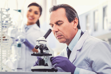 Old chemist wearing gloves working in laboratory