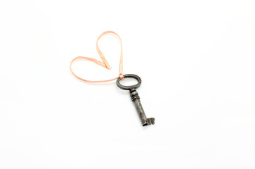 Vintage key with with heart shaped pink ribbon on white