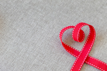 Heart made from red ribbon on linen textile with space for text, Valentine's Day concept.