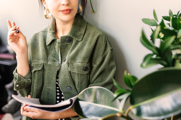 Woman stand at office surround with green plants and write at her note book