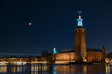 stockholm city hall at night with blood moon in sky